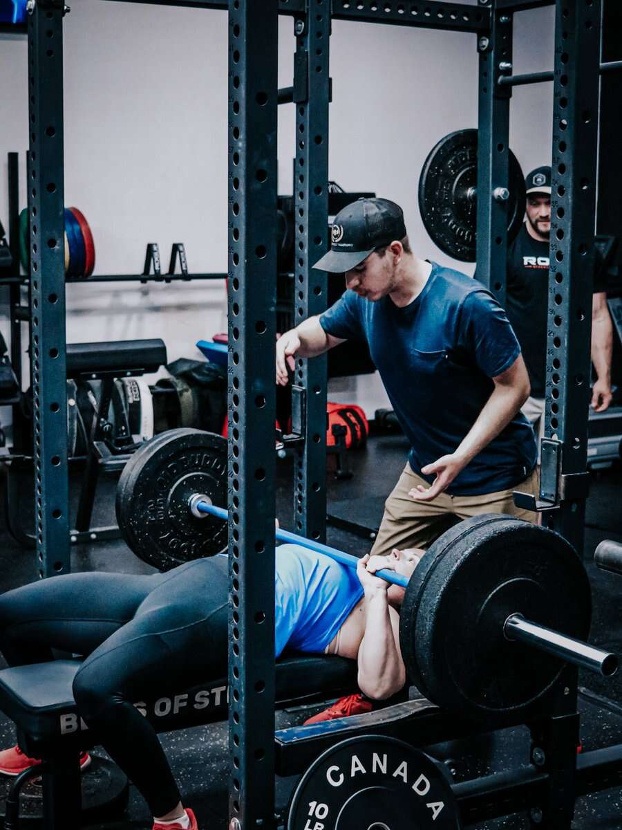 A coach on the floor loading the bar